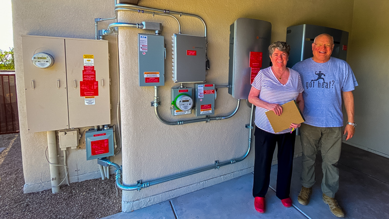 Maggie and Doug in front of the batteries that provide energy security for their Tucson home.